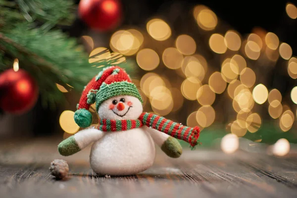 Divertente pupazzo di neve giocattolo sullo sfondo di luci di Natale. — Foto Stock