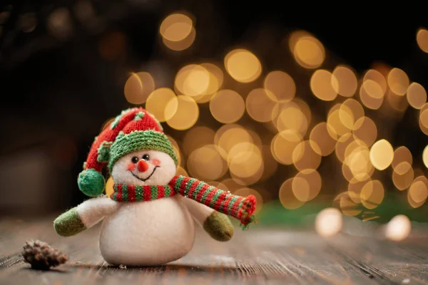 Spielzeug-Schneemann auf dem Hintergrund der Weihnachtsbeleuchtung . — Stockfoto