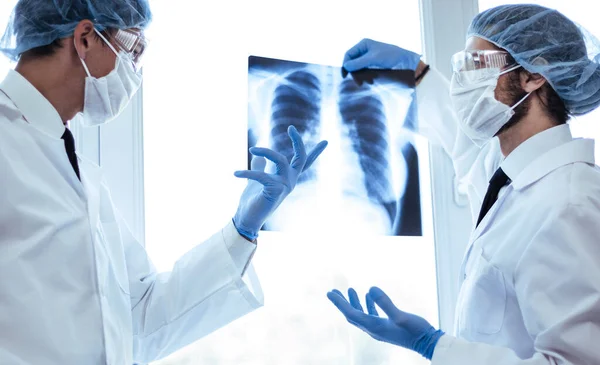 Nahaufnahme. Wissenschaftler in Schutzmasken betrachten ein Röntgenbild der Lungen . — Stockfoto