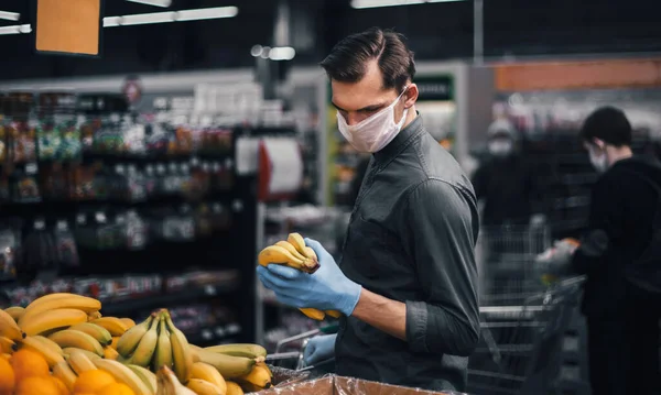 Client en gants de protection choisissant des bananes dans un supermarché — Photo