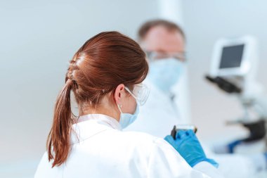 Kapat. Kadın bilim adamı laboratuvarda akıllı telefonunu kullanıyor..