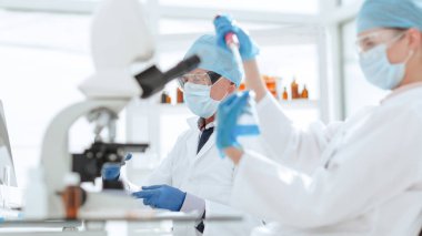 Kapat. Laboratuvar teknisyeni bir laboratuvar şişesinde sıvı test ediyor. .