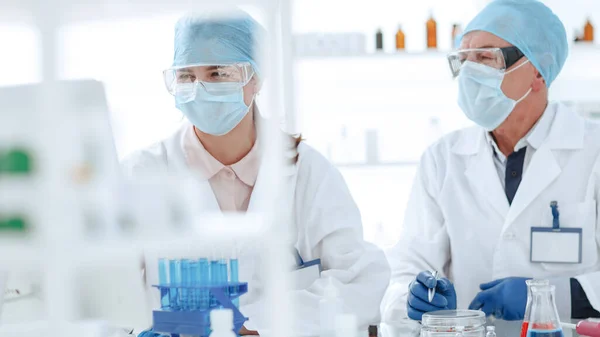 Colegas científicos discutem sentar-se à mesa do laboratório. — Fotografia de Stock