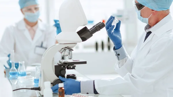 Fecha. cientista ambicioso sentado em uma mesa de laboratório . — Fotografia de Stock