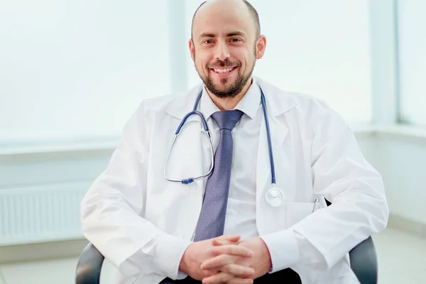 Doctor with a stethoscope sitting at a desk. — Stock Photo, Image