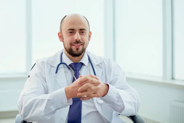 Smiling doctor sitting in a chair and looking at the camera. — Stock Photo, Image