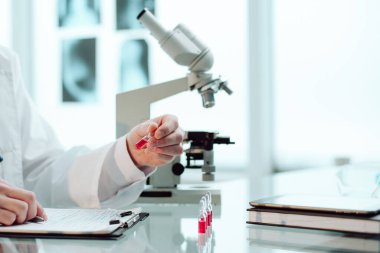 Yakın plan. Araştırmacı test sonuçlarını panoya yazar.