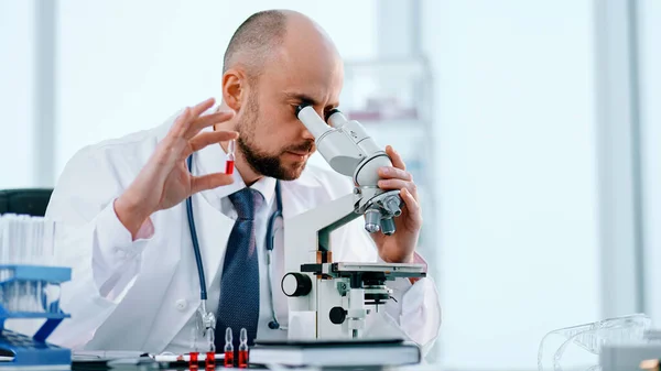 Cientista que estuda amostras de vacinas através de um microscópio . — Fotografia de Stock