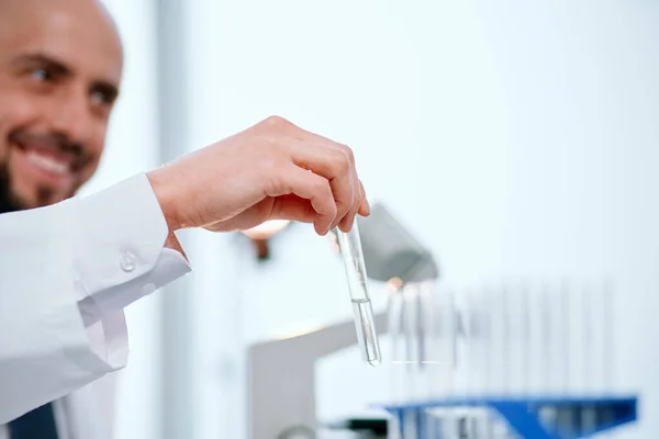 Cientista sorrindo detém um tubo de ensaio com uma amostra da vacina . — Fotografia de Stock