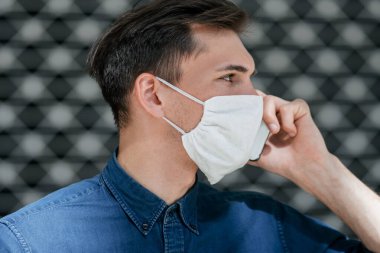 Kapat. Koruyucu maskeli çekici genç adam akıllı telefondan konuşuyor.