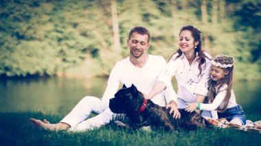 Güneşli bir yaz gününde piknikte köpekli mutlu bir aile. pregn