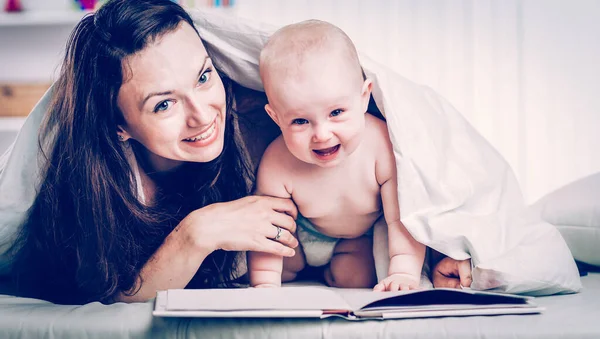 Mãe feliz lendo um livro para ela um ano de idade criança — Fotografia de Stock