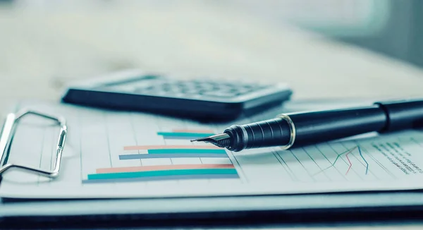 Penna, calcolatrice e grafico finanziario su un posto di lavoro del busine — Foto Stock