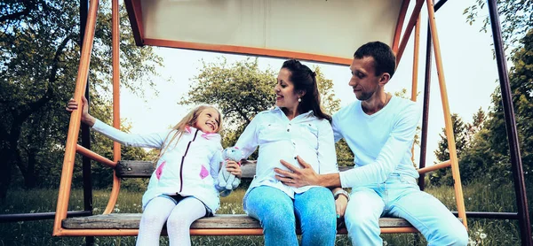 Familia feliz en los columpios en el jardín el domingo —  Fotos de Stock