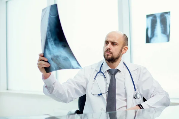 Doctor is carefully looking at the X-ray. — Stock Photo, Image