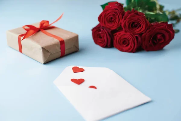 Envelope with valentines, gift box and roses on a blue background. — Stock Photo, Image