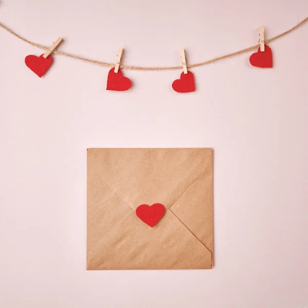 Праздничный конверт и валентинки, прикрепленные к веревке на светлом фоне. — стоковое фото