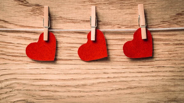 Corações vermelhos em clothespins em fundo de madeira — Fotografia de Stock