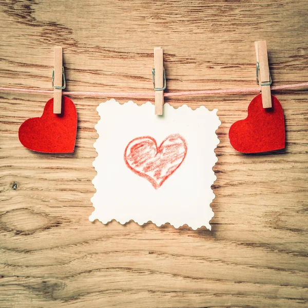 Pinzas de ropa con corazones rojos y una sábana en blanco en una cuerda — Foto de Stock