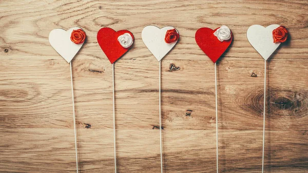 Rij van rode en witte harten met stokken op houten ondergrond — Stockfoto