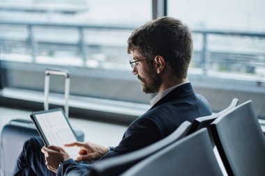 İşadamı dijital tablette çalışıyor, bankta oturuyor.