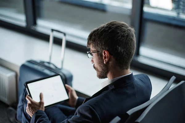 Homme d'affaires réfléchi avec une tablette numérique en attente de son vol. — Photo