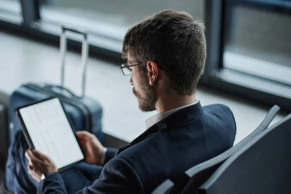Hombre de negocios usando una tableta digital mientras está sentado en un banco en t —  Fotos de Stock