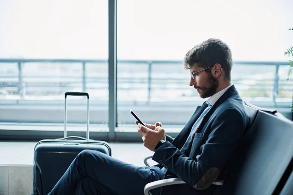 Uomo d'affari che utilizza un tablet digitale in attesa del suo volo Immagine Stock