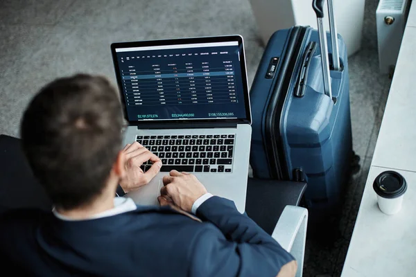 Uomo d'affari che utilizza un computer portatile per chiarire i dati sul suo volo. Fotografia Stock