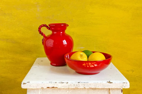 Красная керамика кувшин и тарелка с лимонами — стоковое фото
