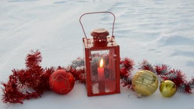 Noel topları ve kar üzerinde mum lamba