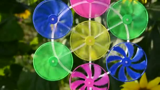 Colorido juguete molino de viento en el jardín y girasoles — Vídeo de stock