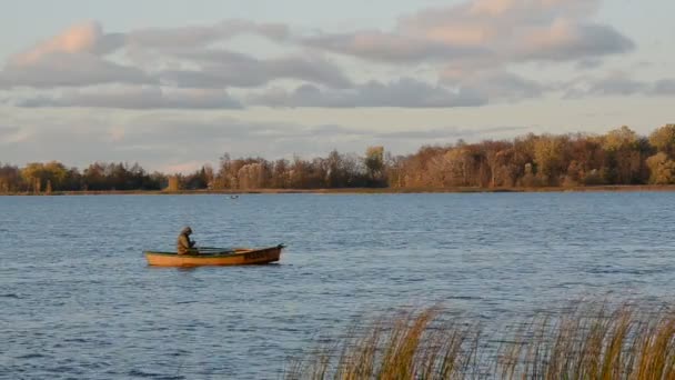 Lago de otoño y barco solitario con pescador — Vídeos de Stock