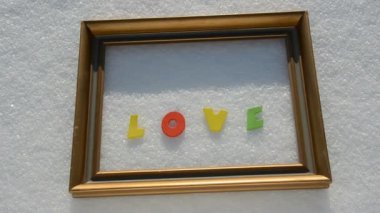 Altın çerçeve üzerinde kar ve kelime aşk