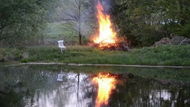 Lente brand in boerderij in de buurt van de vijver en stoel — Stockvideo