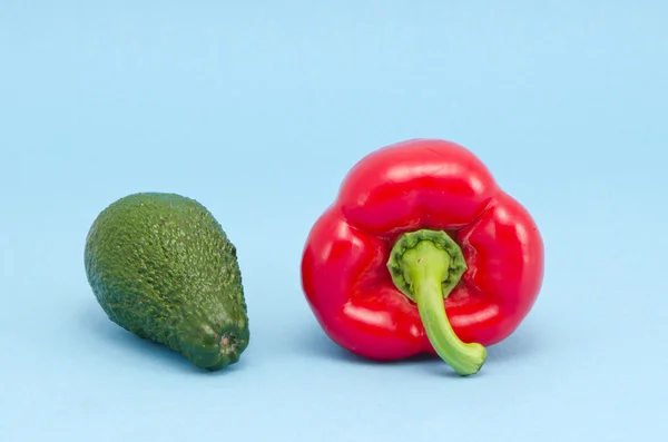 Avocado fresco e pepe rosso su sfondo azzurro — Foto Stock