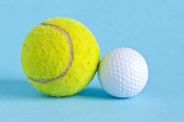 Pelotas de golf y tenis sobre fondo azul — Foto de Stock