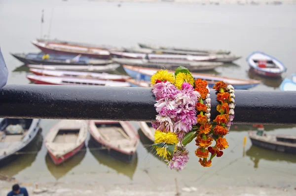 Bloemen en boten in de buurt van ganges rivier in varanasi — Stockfoto