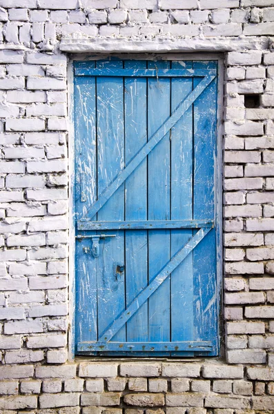 Porta de madeira azul na parede de tijolo branco — Fotografia de Stock