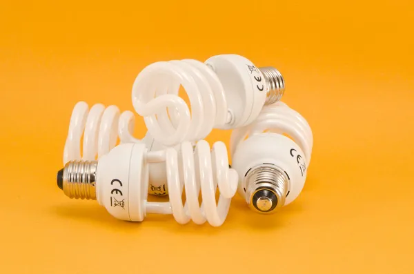 Three modern energy saving electric bulbs on yellow background — Stock Photo, Image