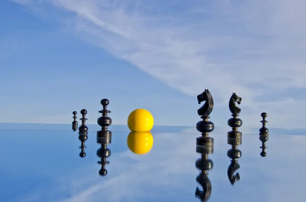 黑棋盘上的棋子和镜像上的黄色台球球 — 图库照片