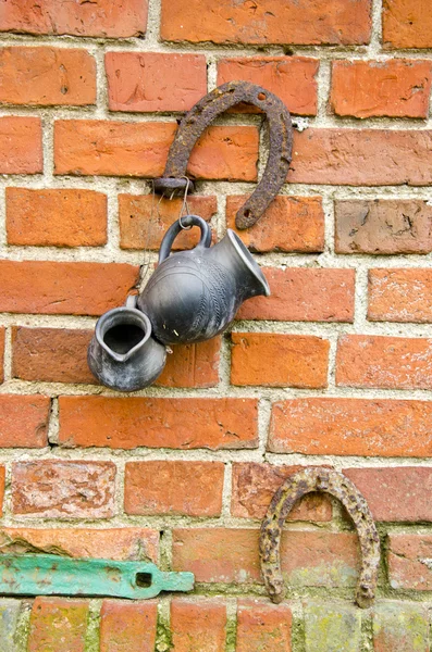 Alte Mauer aus roten Ziegeln mit Hufeisen und Krug — Stockfoto