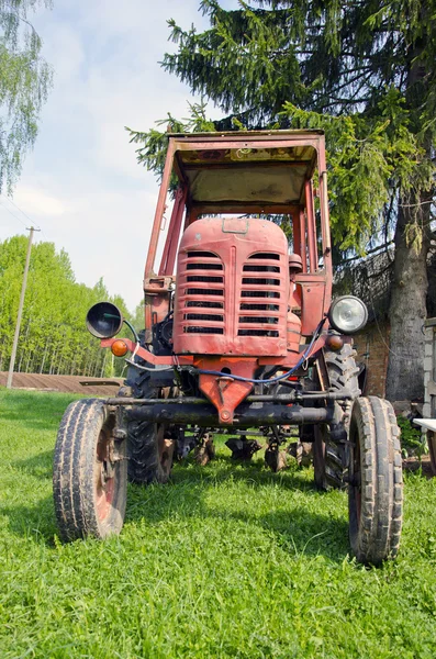 Old red tractor on grass in farm — Stock Photo, Image