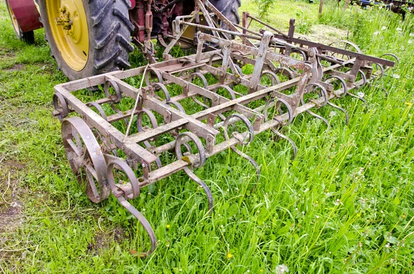 Tractor en el campo de la granja gras con grada de metal — Foto de Stock