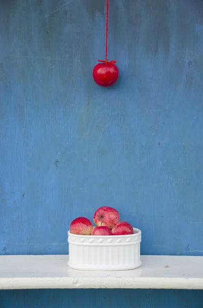 Colgando manzana roja en la cuerda y jarrón blanco con frutas — Foto de Stock