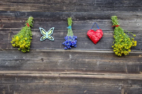 Hanging medical herb bunch and red heart on wall — Stock Photo, Image