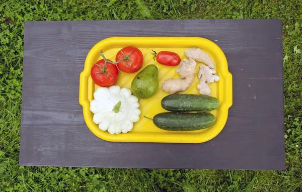 Bandeja de plástico amarelo com legumes de verão na mesa preta — Fotografia de Stock