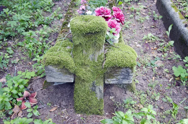 Oude houten kruis met groene mos op de begraafplaats — Stockfoto