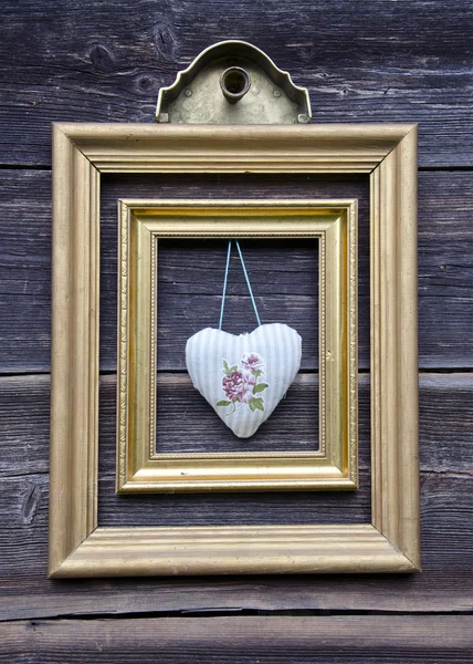 Золотая рамка на деревянной стене и сердце ткани — стоковое фото