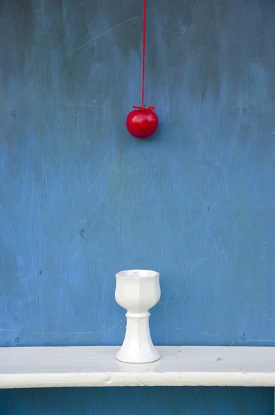 Hängande rött äpple på strängen och vit vas — Stockfoto